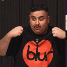 a man is wearing a black shirt with a red circle and the word blur on it