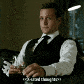 a man in a suit and tie is sitting on a couch holding a glass of wine