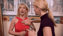 two women standing next to each other with one holding a glass of wine