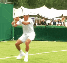 a man in a white shirt and shorts is swinging a tennis racket