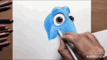 a person is drawing a blue fish on a piece of paper with colored pencils and the words made in animatica at the bottom