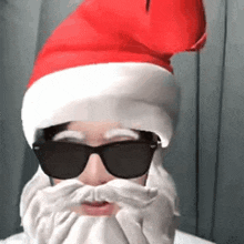 a man is wearing a santa hat and sunglasses and has a beard .