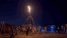 a group of people are gathered around a fire display at night .