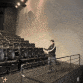 a man is standing in an auditorium with rows of seats and a railing
