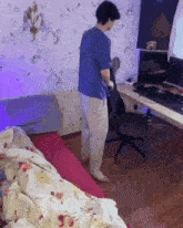 a man in a blue shirt is standing next to a chair in a room