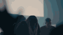 a group of people are standing in a dark room with a woman covering her face .
