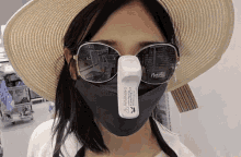 a woman wearing a mask and sunglasses has a warning label on her face