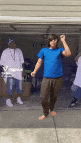 a man in a blue shirt is dancing in front of a garage door ..
