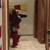 a woman in a red dress is walking down a hallway with other people