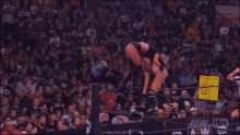 a woman is laying on the ground in a wrestling ring with a referee in the background .
