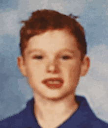 a young boy in a blue shirt looks at the camera