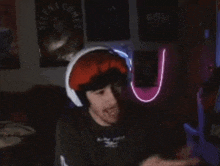a man wearing headphones and a hat is making a funny face in front of a selena gomez poster .