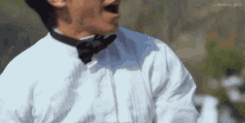 a man wearing a bow tie and a white shirt is screaming .