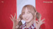 a woman with pigtails is smiling and making a peace sign with her hands