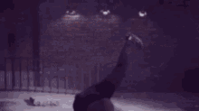 a man wearing a white shirt and a hat is dancing in front of a brick wall .