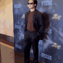 a man in a suit stands in front of a wall that says " beyond the stars "