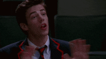 a man in a suit and tie is making a face with his hands outstretched