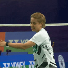 a woman in a white shirt is playing badminton in front of a yonex advertisement