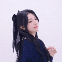 a woman in a blue sweater has a black ribbon in her hair