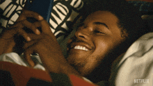 a man is laying in bed looking at his phone with a netflix logo on the bottom right