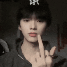 a young man wearing a new york yankees hat is giving the middle finger .
