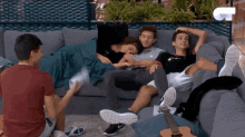 a group of people are laying on a couch with a guitar