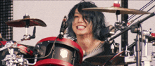 a man is playing drums and smiling in front of a microphone