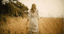 a woman in a dress is walking through a field