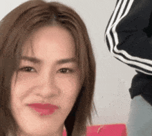 a close up of a woman 's face with a pink purse behind her