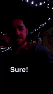 a man in a dark room with the word sure written on the bottom