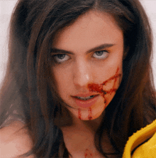 a woman with blood on her face is wearing a yellow shirt