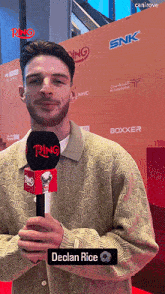 a man is holding a ring microphone in front of an orange wall