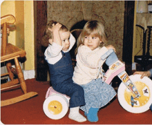 a boy and a girl are playing with a tricycle that says fisher price