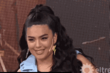a woman wearing a lightning bolt earring and a lightning bolt jacket is smiling .