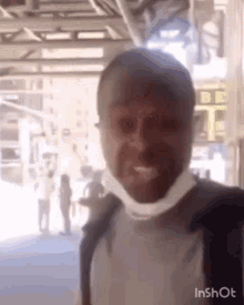 a man wearing a mask is making a funny face while standing in front of a building .