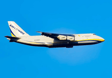 a large antonov airplane is flying through a blue sky