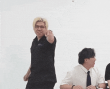 a man wearing glasses and a nasa shirt points at something