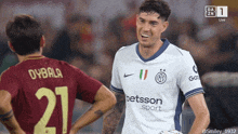 a soccer player wearing a betsson sport jersey stands next to another player