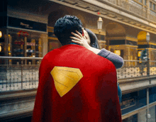 a man in a superman cape is being hugged by a woman