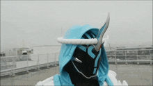 a person wearing a blue hooded jacket with a white ribbon around their head
