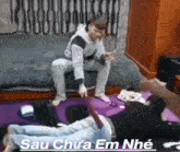 a man is sitting on a couch next to a man laying on the floor .