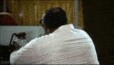a man in a white shirt is looking at himself in a mirror .
