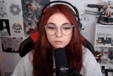 a girl with red hair and glasses is wearing headphones and a microphone .
