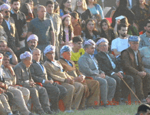 a group of people sitting in a field with a photo taken on march 5th 2015