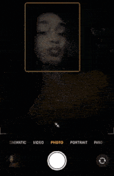 a phone screen shows a woman taking a picture of herself with the option to take a portrait