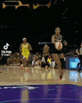 two women are playing basketball on a court and one of them is holding a ball .