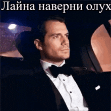 a man in a suit and bow tie is sitting in a car .