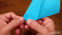 a person is holding a blue paper airplane in their hands made in animatica