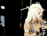 a woman with blonde hair singing into a microphone in a dark room