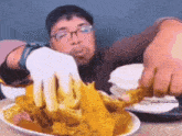 a man wearing glasses is eating a plate of food .